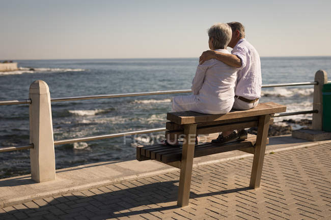 Senior couple sitting on bench near sea side at promenade — Stock Photo
