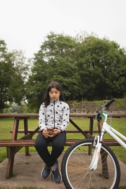 Young girl using mobile phone at garden — Stock Photo
