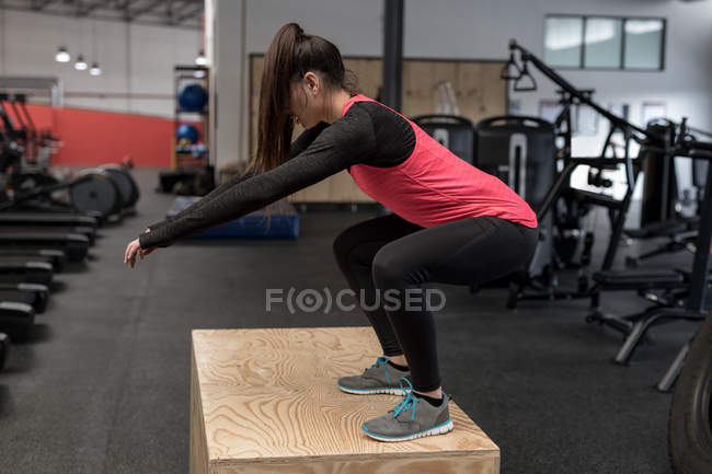 Young woman doing squat exercise in fitness studio — Stock Photo