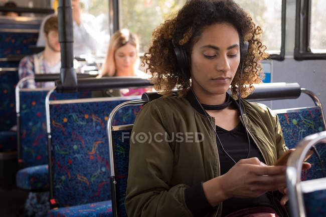Молодая женщина пригородных прослушивания музыки во время путешествия в современном автобусе — стоковое фото