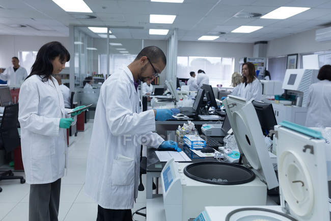 Equipo de técnicos de laboratorio trabajando juntos en banco de sangre - foto de stock