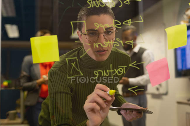 Бизнесмен пишет на стеклянной доске в офисе — стоковое фото