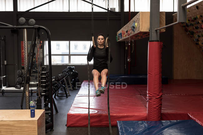 Красива жінка робить підтягування на гімнастичні кільця в фітнес-залі — стокове фото