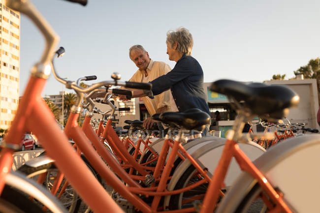 Smiling senior couple parking bicycle on a sunny day — Stock Photo