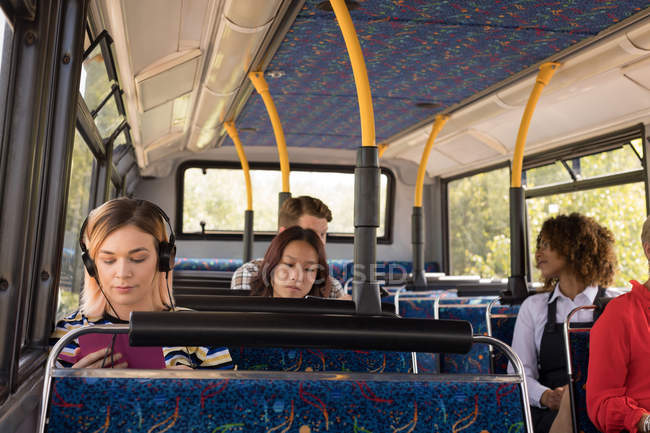 Female commuter listening music while travelling in modern bus — Stock Photo