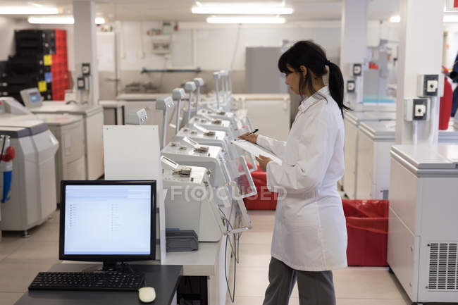 Técnico de laboratório escrevendo na área de transferência no banco de sangue — Fotografia de Stock