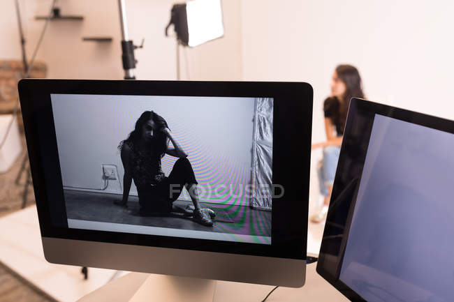 Modelo femenino posando en la pantalla del ordenador en el estudio de fotos - foto de stock