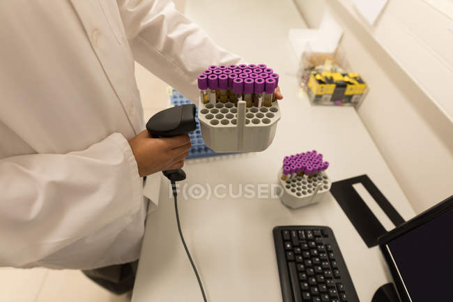 Technicien de laboratoire scannant le code à barres du support de tube à essai dans la banque de sang — Photo de stock