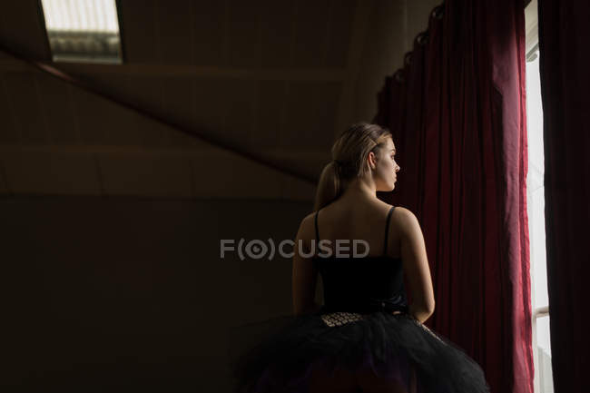 Nachdenkliche Ballerina blickt durch Fenster im Atelier — Stockfoto