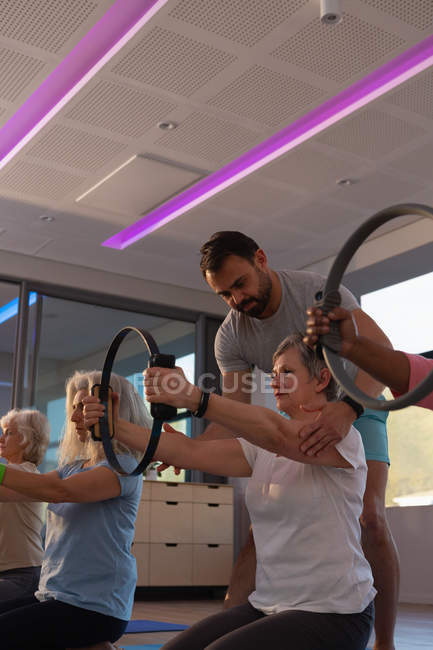 Тренер, помогающий старшим женщинам в йоге в центре йоги — стоковое фото