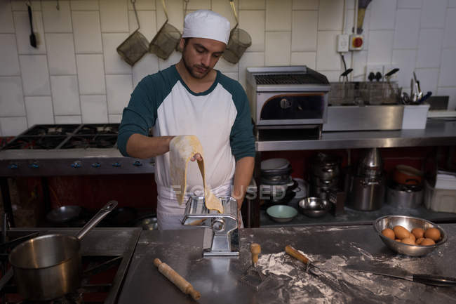 Baker using machine for preparing pasta in bakery — Stock Photo