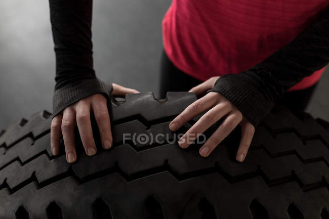 Partie médiane de la femme faisant de l'exercice avec un pneu dans un studio de fitness — Photo de stock