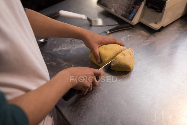 Männerbäcker schneidet Teig in Bäckerei — Stockfoto
