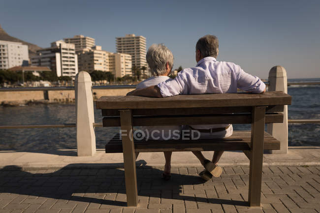 Вид ззаду старшої пари, що сидить на лавці на набережній — стокове фото