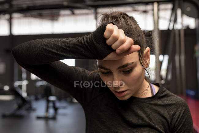 Young woman wipes sweat after workout in fitness studio — Stock Photo