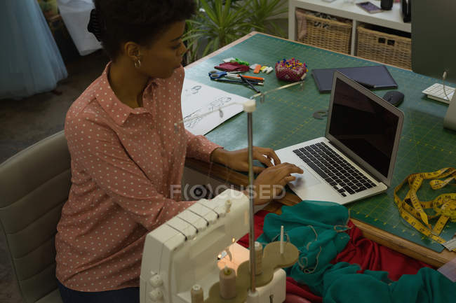Designer de moda usando laptop na mesa no estúdio de moda — Fotografia de Stock