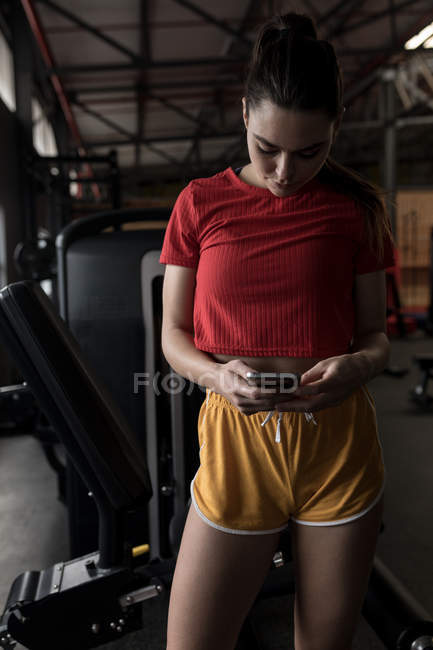 Beautiful woman using mobile phone in fitness studio — Stock Photo