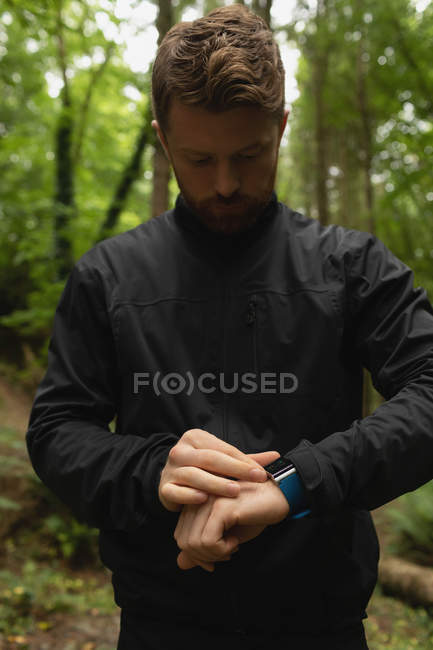 Giovane utilizzando orologio intelligente nella foresta — Foto stock