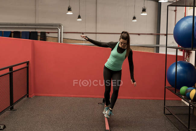 Young woman doing exercise with rubber band in fitness gym — Stock Photo