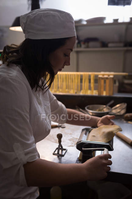 Boulangerie féminine utilisant la machine pour préparer les pâtes dans la boulangerie — Photo de stock