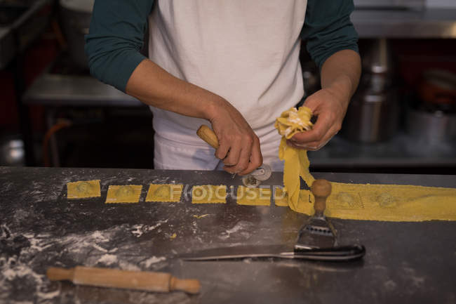 Parte centrale del panettiere maschile che prepara la pasta in panetteria — Foto stock