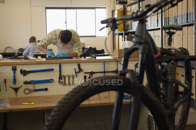 Мужчина чистит детали велосипеда на прилавке в мастерской — стоковое фото