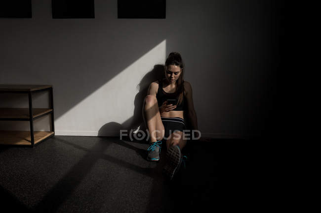 Mulher bonita usando telefone celular no estúdio de fitness — Fotografia de Stock