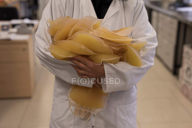 Технік-лаборант тримаючись за зразки крові банку — стокове фото