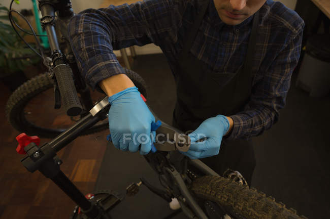 Young man repairing bicycle in workshop — Stock Photo