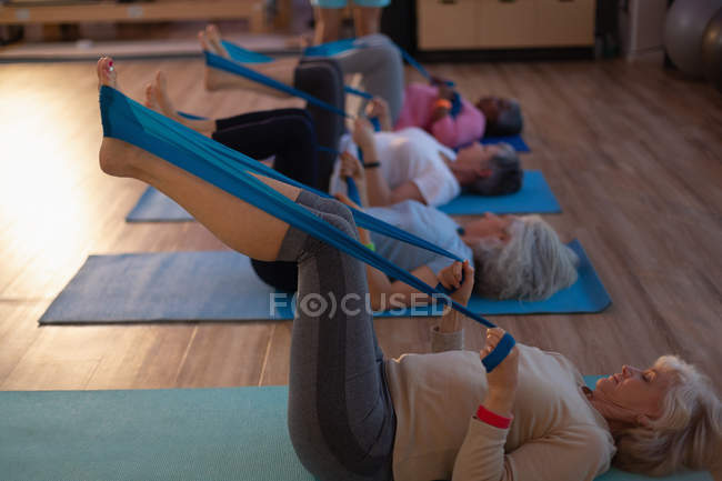 Gruppo di donne anziane che praticano yoga con una fascia di yoga nel centro yoga — Foto stock