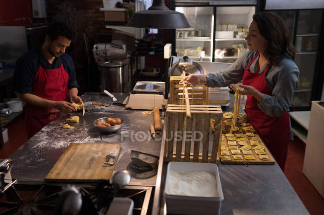 Baker preparing handmade pasta with other in bakery — Stock Photo
