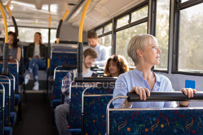 Female commuter looking through window while travelling in modern bus — Stock Photo