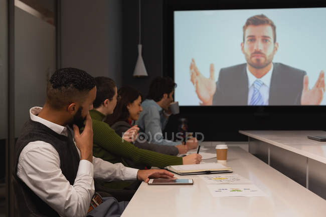 Gente de negocios interactuando a través de videollamadas en la oficina - foto de stock