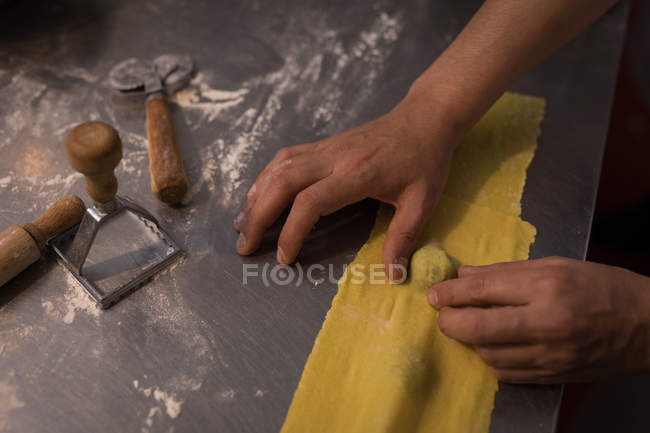 Крупный план пекаря мужского пола, готовящего макароны в пекарне — стоковое фото