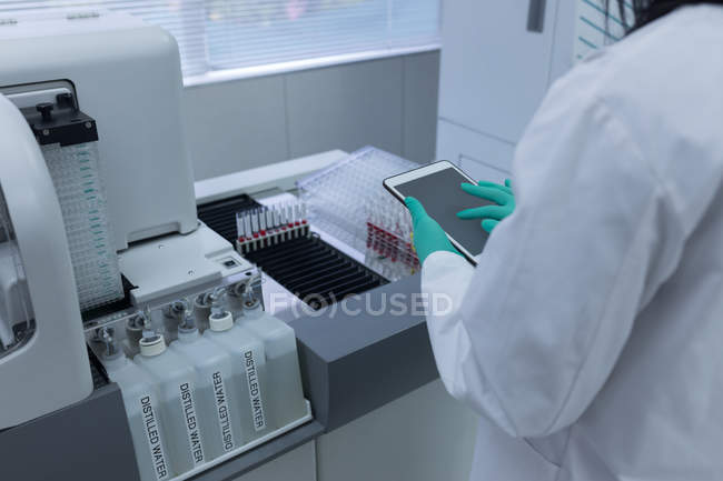 Técnico de laboratorio usando tableta digital en banco de sangre - foto de stock