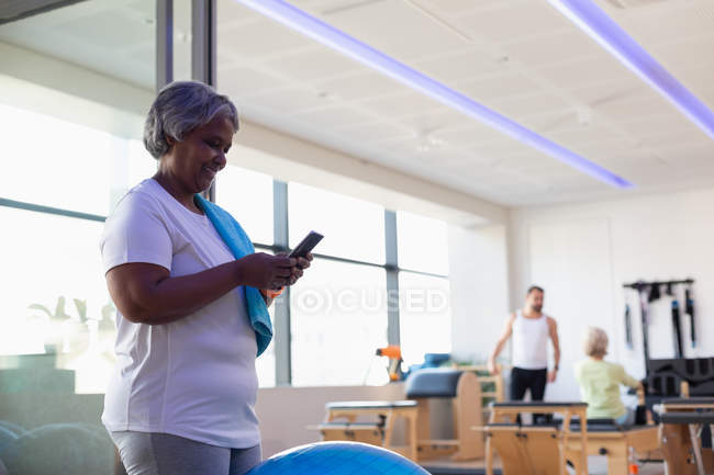 Happy senior women using mobile phone in yoga center — Stock Photo