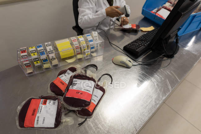 Técnico de laboratorio escaneando código de barras de bolsas de sangre en banco de sangre - foto de stock