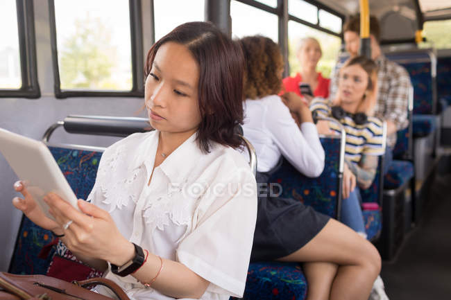 Жіночий комп'ютер з використанням цифрового планшета під час подорожі в сучасному автобусі — стокове фото