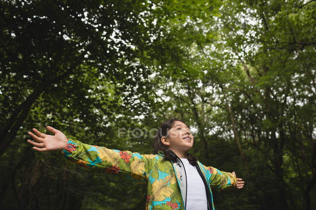 Young girl with arms outstretched standing in forest — Stock Photo