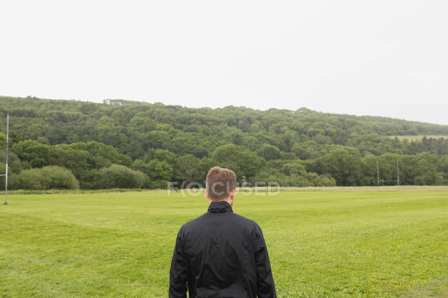 Вид сзади на человека, стоящего на зеленом ландшафте — стоковое фото