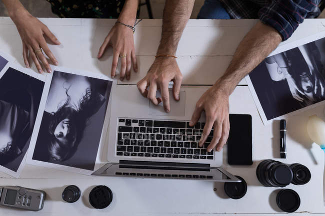 Средняя секция мужского и женского фотографа с помощью ноутбука в фотостудии — стоковое фото