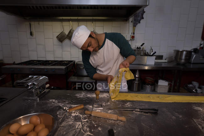 Panadero masculino preparando pasta en panadería - foto de stock