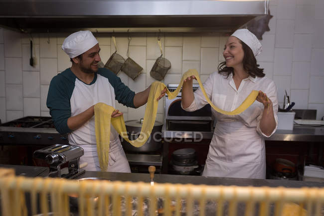 Улыбающиеся пекари готовят макароны в пекарне — стоковое фото