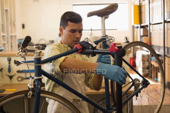 Mann montiert Fahrrad auf Reparaturständer in Werkstatt — Stockfoto