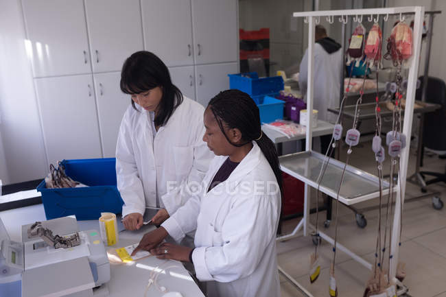 Técnico de laboratório escrevendo em uma etiqueta no banco de sangue — Fotografia de Stock