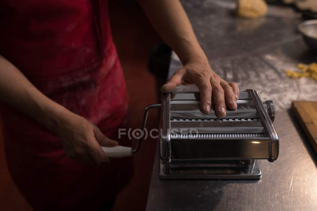 Mid section of baker using pasta machine in bakery — Stock Photo