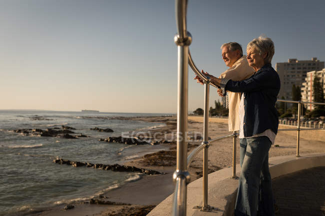 Старша пара стоїть на набережній біля моря в сонячний день — стокове фото