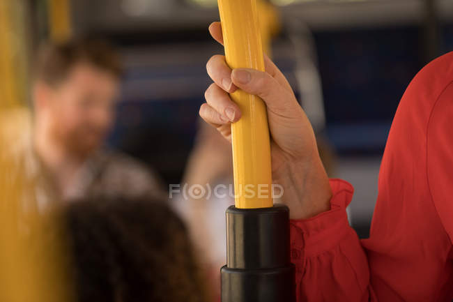 Крупный план женщины, держащей столб во время путешествия в современном автобусе — стоковое фото