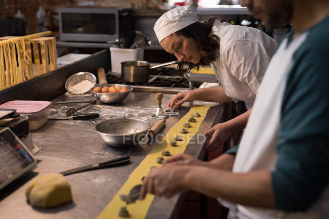 Panaderos atentos preparando pasta en panadería - foto de stock