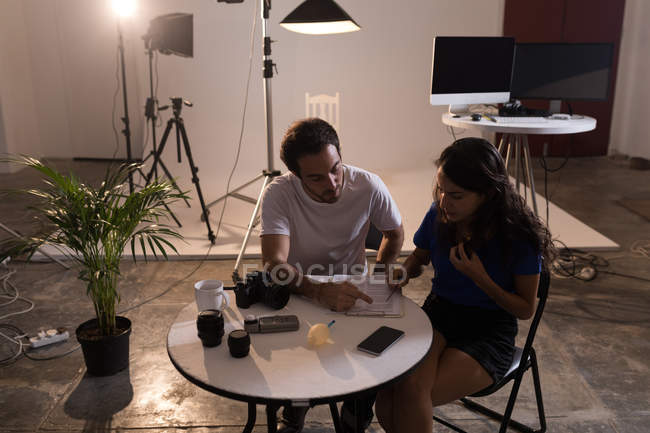 Fotógrafo masculino e modelo feminino escrevendo na área de transferência no estúdio de fotografia — Fotografia de Stock